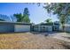 A blue home featuring a brick walkway, a detached garage, lush trees, and sunny skies at 10952 61St Ave, Seminole, FL 33772