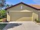 Beige two-car garage with a tile roof and neutral color scheme blends well with the surrounding landscape at 5485 Sunset Falls Dr, Apollo Beach, FL 33572