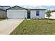 Exterior showcasing a white one-story house with a green lawn, driveway, and blue sky at 31632 Malbec Dr, Brooksville, FL 34602
