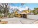 The yellow home has a large driveway, white fence, and a covered area with ample parking at 8135 33Rd Ave N, St Petersburg, FL 33710