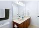 Bathroom featuring a double sink vanity with cherry wood cabinets, large mirror, and decorative towels at 8539 Sandpiper Ridge Ave, Tampa, FL 33647