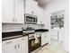 Well-lit kitchen with white cabinets, stainless steel appliances, and adjacent laundry room at 8539 Sandpiper Ridge Ave, Tampa, FL 33647