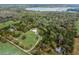 This aerial shot displays a sprawling property with mature trees, a home, and the serene backdrop of a lake at 18526 Sweetbay Ln, Dade City, FL 33523