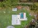 Aerial shot showcases a home with a screened pool, accented by an umbrella, set on lush grounds at 18526 Sweetbay Ln, Dade City, FL 33523