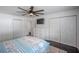 Well-lit bedroom features a ceiling fan, dark hardwood floors, a TV, closet space, and a dresser at 18526 Sweetbay Ln, Dade City, FL 33523
