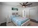 A bright bedroom featuring a ceiling fan, dark hardwood floors, and a full bed with matching end tables at 18526 Sweetbay Ln, Dade City, FL 33523