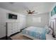 A bright bedroom is shown featuring a ceiling fan, hardwood floors, a full bed, a dresser, and closet space at 18526 Sweetbay Ln, Dade City, FL 33523