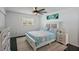 Bright bedroom with a ceiling fan, dark hardwood floors, and a white bed with blue accents at 18526 Sweetbay Ln, Dade City, FL 33523