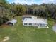 Exterior angle showcases a home with a metal roof, carport, screened pool area, and surrounding greenery at 18526 Sweetbay Ln, Dade City, FL 33523