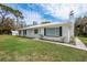 Inviting home featuring a white brick exterior, metal roof, and lush green lawn at 18526 Sweetbay Ln, Dade City, FL 33523