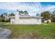 View of the side of the home featuring the chimney, a door, and an additional structure at 18526 Sweetbay Ln, Dade City, FL 33523