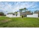 Exterior view of a charming white house with a screened-in patio and lush green lawn at 18526 Sweetbay Ln, Dade City, FL 33523