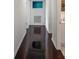 A bright hallway featuring dark wood flooring and white walls leading to a bathroom at 18526 Sweetbay Ln, Dade City, FL 33523