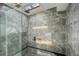 This tiled shower features a frameless glass door and a skylight to let in natural light at 18526 Sweetbay Ln, Dade City, FL 33523