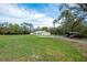 Expansive yard featuring a white home with metal roof, shed, and vehicle storage at 18526 Sweetbay Ln, Dade City, FL 33523