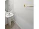 Simple powder room featuring pedestal sink, round mirror, gold towel rack, and a light beige tile floor at 2921 Flowering Moss Run, Wesley Chapel, FL 33543