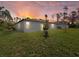 Sunset view of a backyard featuring a lush lawn and the home's exterior at 24299 Kingsway Cir, Punta Gorda, FL 33983