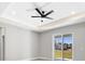 Bedroom featuring tray ceilings, fan and sliding glass doors leading to the backyard at 24299 Kingsway Cir, Punta Gorda, FL 33983