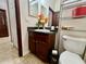Bathroom with vanity and sink with black countertop, shelf, toilet and tiled flooring at 724 Parker Den Dr, Ruskin, FL 33570