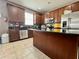 Well-lit kitchen featuring wood cabinets, stainless steel appliances, and a functional center island with tile floors at 724 Parker Den Dr, Ruskin, FL 33570