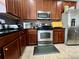 A kitchen featuring stainless steel appliances, wood cabinetry, granite countertops, and tile flooring provides great functionality at 724 Parker Den Dr, Ruskin, FL 33570