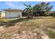View of the backyard featuring a one-car garage, screened in patio, and open grassy space at 18284 Yale Ave, Port Charlotte, FL 33948