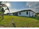 Backyard of home featuring an enclosed lanai, green grass, and partial views of the surrounding neighborhood at 24470 Kingsway Cir, Punta Gorda, FL 33983