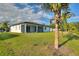 Expansive backyard featuring a screened lanai, lush green lawn, and mature palm trees at 24470 Kingsway Cir, Punta Gorda, FL 33983