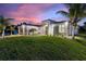 A modern home accentuated by palm trees, complemented by vibrant lawn and concrete driveway at 24470 Kingsway Cir, Punta Gorda, FL 33983