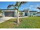 Charming modern home featuring a two-car garage, complemented by a landscaped yard and decorative palm tree at 24470 Kingsway Cir, Punta Gorda, FL 33983