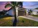 Property showcasing a dark garage door framed by stylish lighting and a pristine driveway at 24470 Kingsway Cir, Punta Gorda, FL 33983