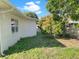 Side yard surrounded by grass, house, fence and a mature flowering tree at 301 Francis Dr, Apollo Beach, FL 33572