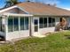 Enclosed sunroom with bright windows is attached to the home's exterior with a manicured lawn at 1110 Mcdaniel St # 1110, Sun City Center, FL 33573