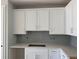 Modern kitchen features new white cabinets with gray backsplash and quartz countertops with a stainless steel sink at 7268 Deer Valley Circle, Tampa, FL 33635