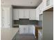 Modern kitchen features new white cabinets, gray backsplash, gray wood-look tile floors, and quartz countertops at 7268 Deer Valley Circle, Tampa, FL 33635