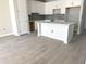 Spacious kitchen features new white cabinets, gray backsplash, quartz countertops, island, and wood-look tile at 7268 Deer Valley Circle, Tampa, FL 33635