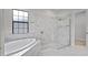 Sleek bathroom showcasing a soaking tub, glass-enclosed shower, and modern marble-look tile at 5516 Madrigal Way, Apollo Beach, FL 33572