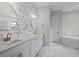 Luxury bathroom featuring dual sinks, white cabinetry, designer wallpaper, and a soaking tub at 5516 Madrigal Way, Apollo Beach, FL 33572