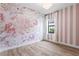 Pretty bedroom with floral wallpaper, wood floors, chandelier lighting and natural light from a window at 5516 Madrigal Way, Apollo Beach, FL 33572
