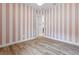 Bright room featuring hardwood floors and pink and white striped walls with white doorframes and modern ceiling fan at 5516 Madrigal Way, Apollo Beach, FL 33572