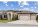 A charming single-Gathering home featuring a three-car garage, arched entrance, and a lush, green lawn at 5516 Madrigal Way, Apollo Beach, FL 33572