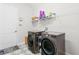 Modern laundry room featuring updated washer and dryer units, shelving and a white door at 5516 Madrigal Way, Apollo Beach, FL 33572