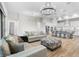 Open-concept living room with modern chandelier, wood floors, and adjoining kitchen at 5516 Madrigal Way, Apollo Beach, FL 33572