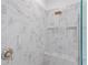 Close-up of a modern shower with marble-look tile, built-in shelves and bench, and bronze hardware at 5516 Madrigal Way, Apollo Beach, FL 33572