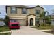 Charming two-story home with a well-maintained lawn and a driveway, accompanied by palm trees in the front yard at 14825 Crescent Rock Dr, Wimauma, FL 33598