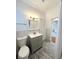 Updated bathroom features gray vanity, white fixtures, wood-look tile, and ample light at 3025 W North A St, Tampa, FL 33609
