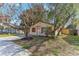 Charming single-story home with orange shutters, surrounded by mature trees and lush landscaping in a vibrant neighborhood at 4046 Las Vegas Dr, New Port Richey, FL 34653
