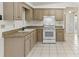 Cozy kitchen featuring light-colored cabinets, white appliances, and tile flooring at 4046 Las Vegas Dr, New Port Richey, FL 34653