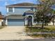 Two-story blue home with an attached garage, lush green lawn, and attractive landscaping at 11406 Holmbridge Ln, Riverview, FL 33579