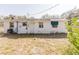 View of backyard and back of a single-story home with patches of grass and some boarded-up windows at 1825 134Th St, Largo, FL 33778